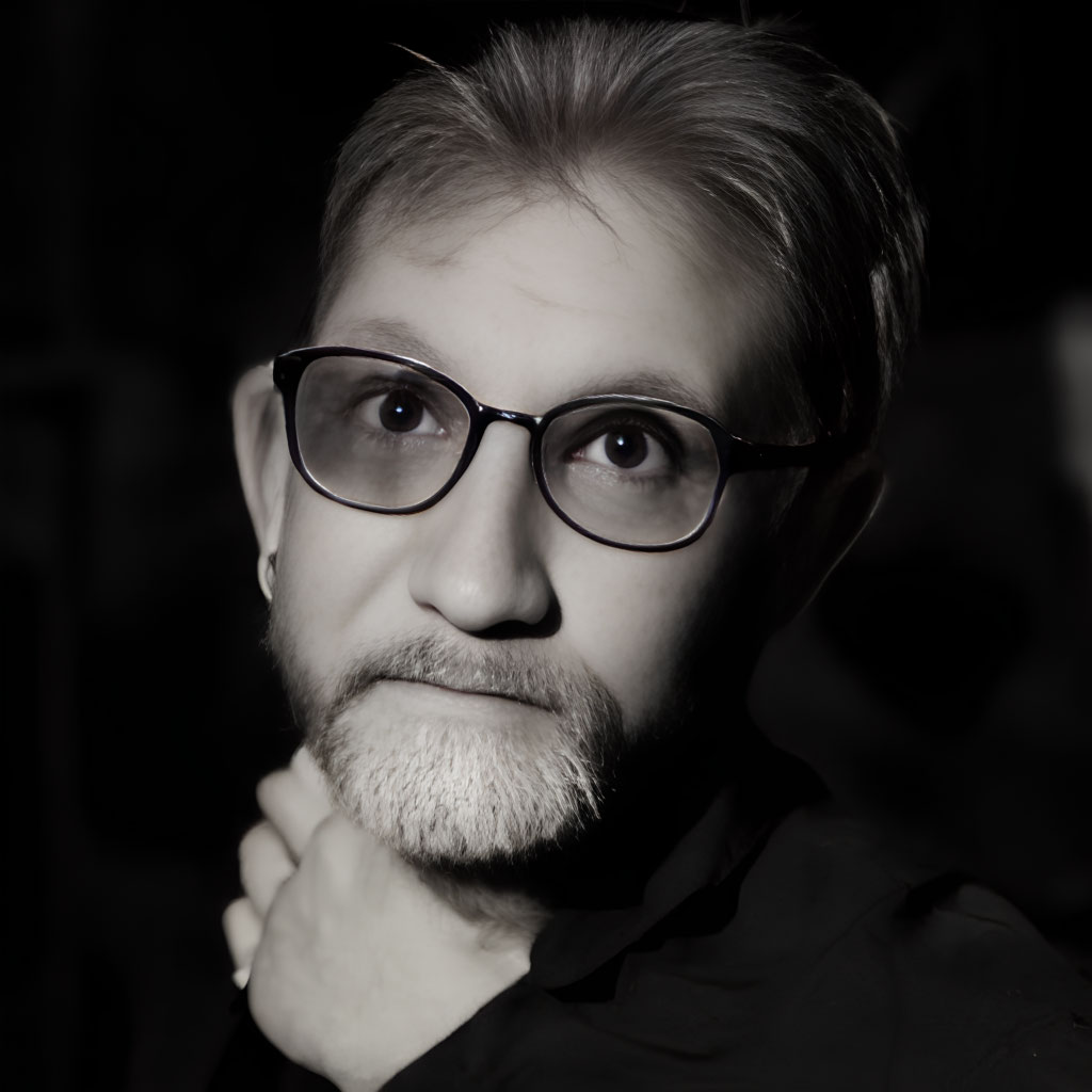 Monochrome portrait of bearded person with glasses in thoughtful pose.