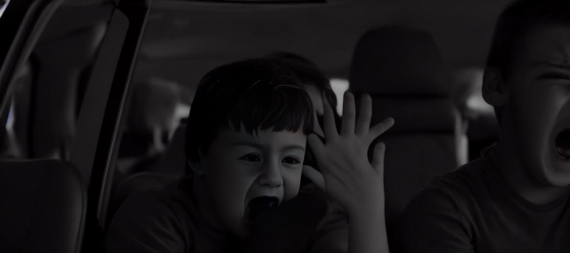 Distressed children in car: one crying, one yelling, monochrome.