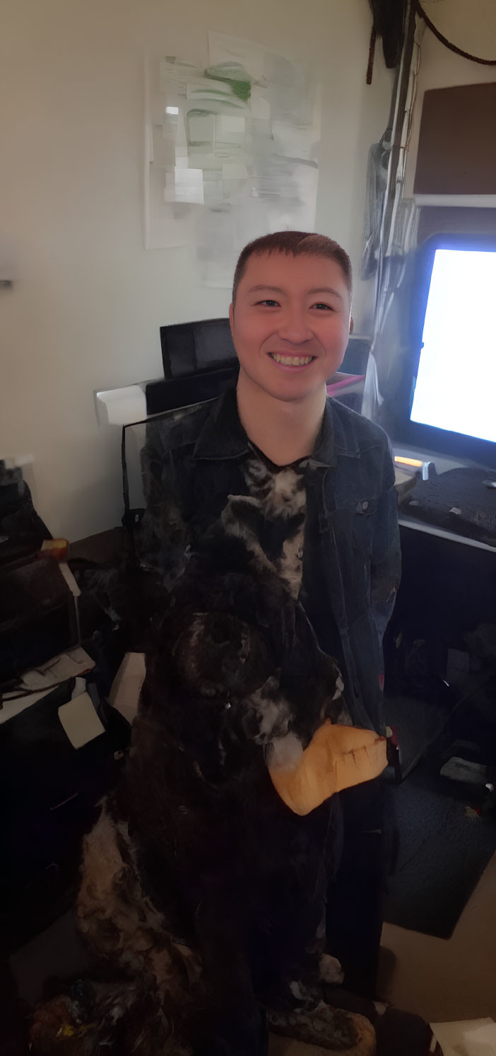 Smiling person in denim jacket with black and white dog in office room