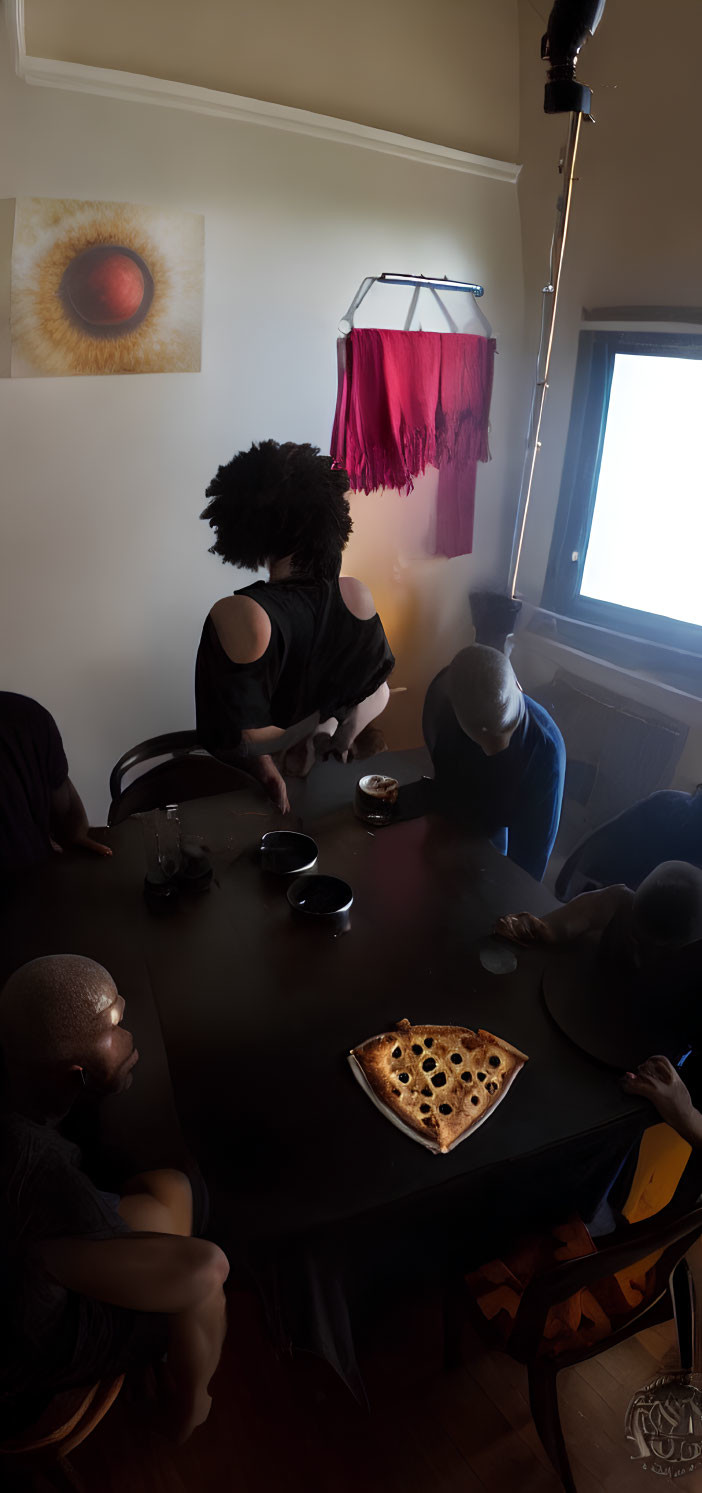 Four People Around Table with Pizza and Wall Artwork