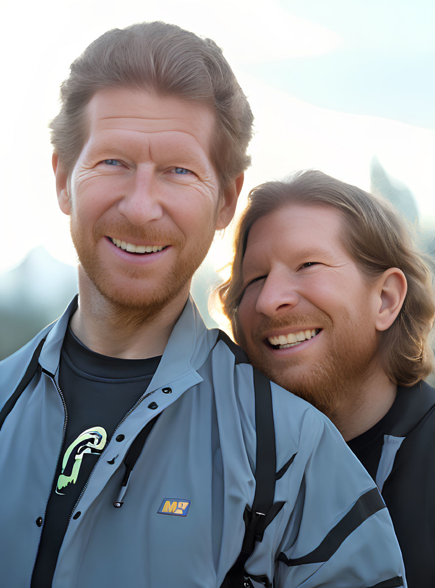 Two smiling men in casual jackets embracing outdoors with soft lighting