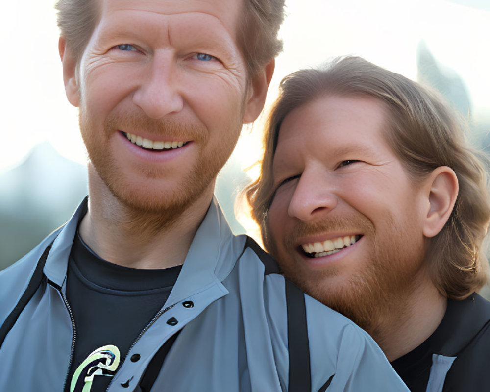 Two smiling men in casual jackets embracing outdoors with soft lighting