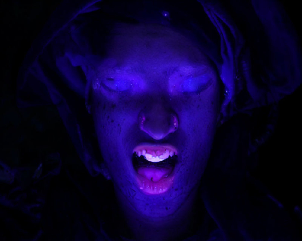 Portrait of person with closed eyes under haunting blue light