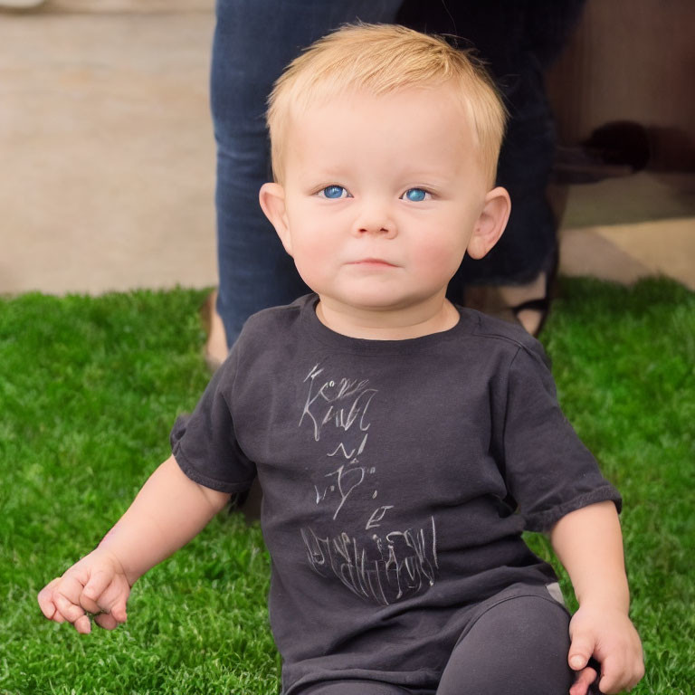 Blonde Toddler with Blue Eyes Sitting on Grass