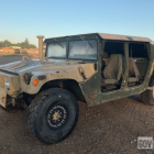 Two people in hats inside a Humvee in desert terrain