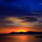 Colorful sunset sky over mountains and lake with crescent moon