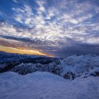 Snow-covered hills and village at sunrise in serene winter landscape