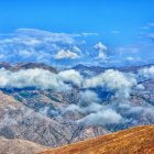 Surreal landscape with blue hills, white clouds, and colorful vegetation