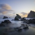 Serene sunrise landscape with mist, dense forests, vibrant sky, and celestial bodies