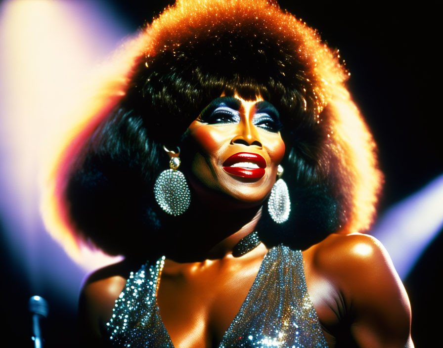 Performer with Large Afro, Sparkling Dress, and Dramatic Makeup Smiles on Stage