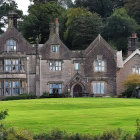 Gothic-style mansion in twilight forest with cloaked figure