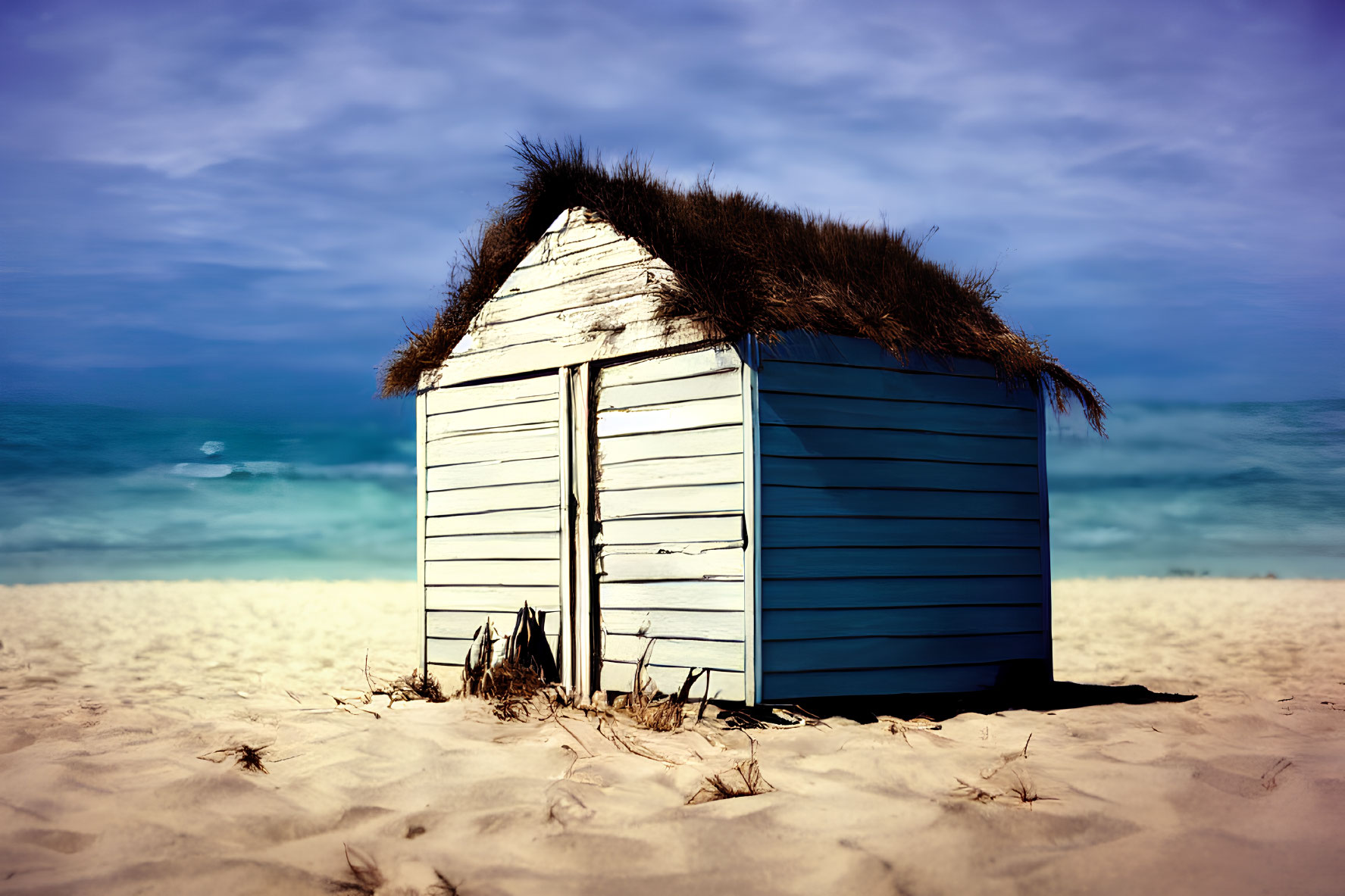 Thatched roof blue beach hut on sandy shore with ocean and clear sky