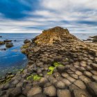 Hexagonal Rock Formations and Cliffside House on Dramatic Coastal Landscape