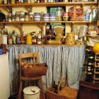 Pantry filled with preserved fruits, oils, fresh fruits, and fabrics