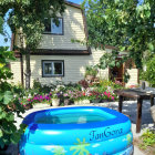 Tranquil courtyard with blue pool, vibrant flowers, climbing vines, and yellow house.