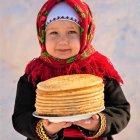 Vintage woman in red dress and apron with pancake in kitchen