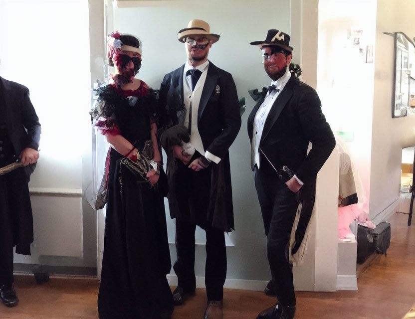 Three People in Vintage Costumes with Top Hats, Suits, and Feathered Mask Holding Small Dog