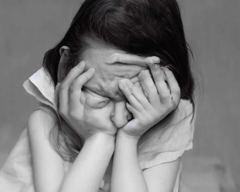 Monochrome image of distressed child with hands covering face