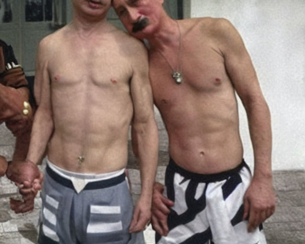 Two shirtless men in striped pants with matching facial hair, one with a mustache