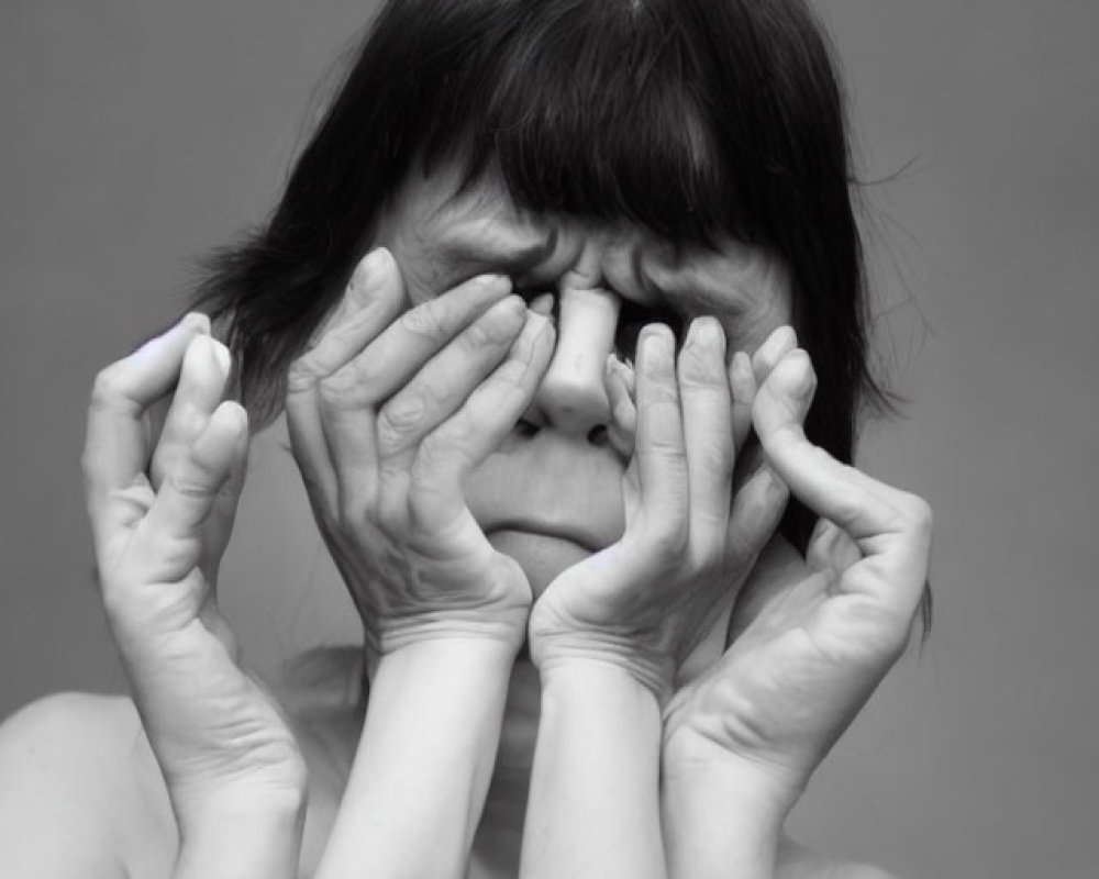 Monochrome portrait of person looking through fingers as glasses