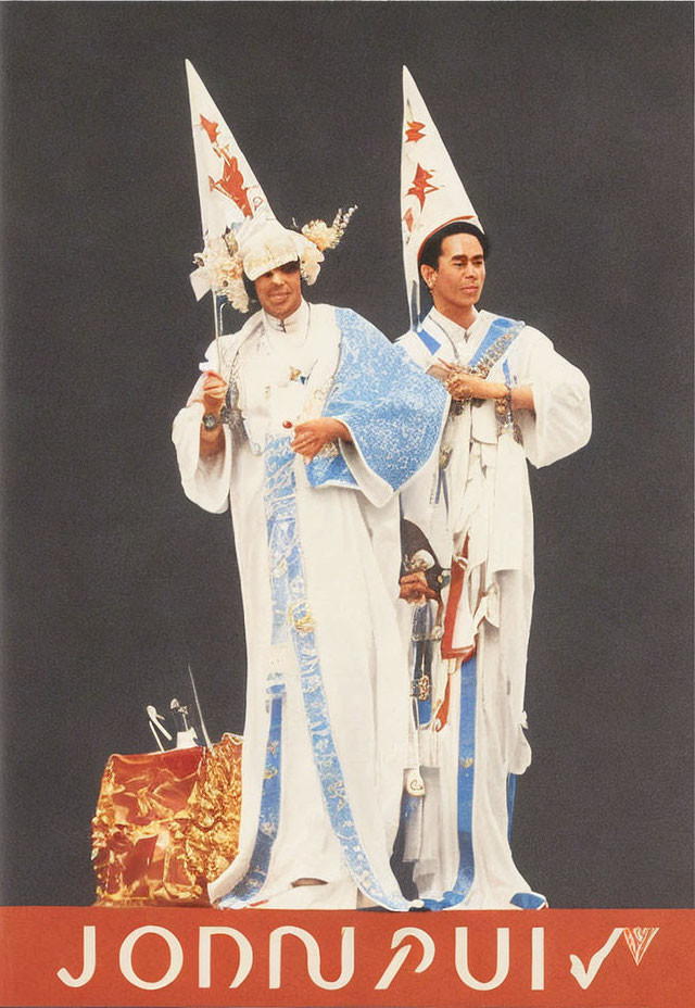 Elaborate White Costumes with Pointed Hats and Thai Text Backdrop