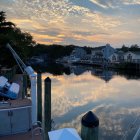 Tranquil sunset over serene harbor with reflections, dock, and boat