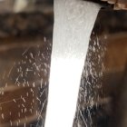 Modern showerhead with flowing water and light reflections on decorative backdrop