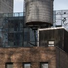 Colorful water tower illustration on brick building with lush greenery and blue sky.