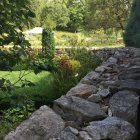 Stone cottages, lush greenery, stone wall, flowers in serene setting