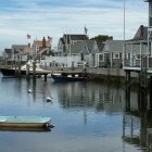 Tranquil marina scene with colorful houses, moored boats, and person rowing.