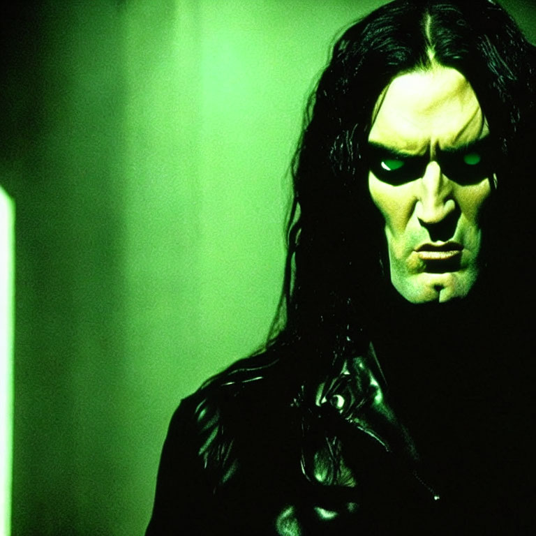 Portrait of Person with Long Dark Hair and Stern Expression in Black Clothing against Green-lit Background