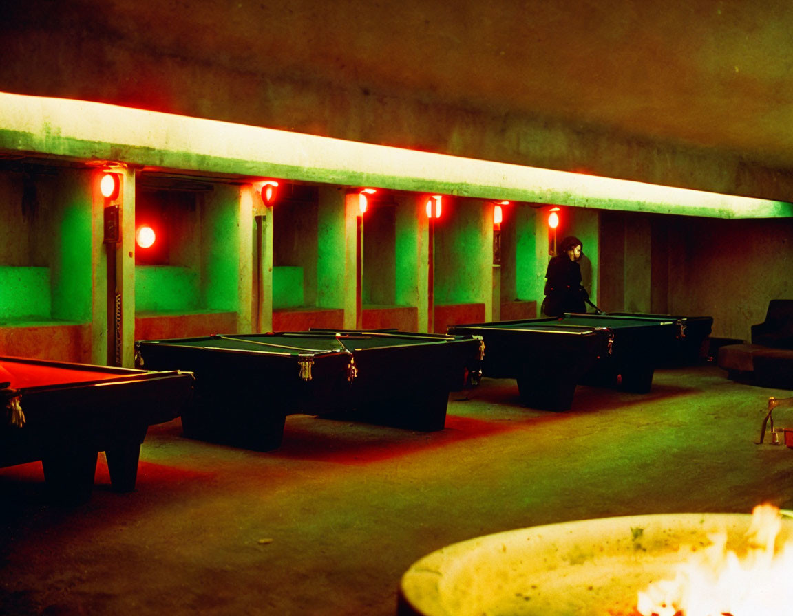 Dimly Lit Room with Pool Tables, Person, and Fireplace