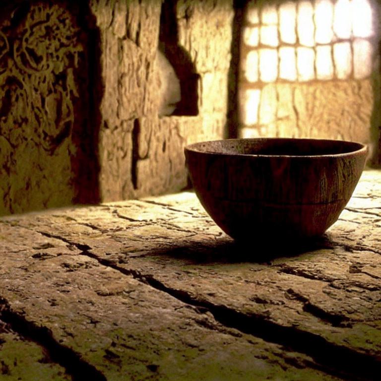 Rustic wooden bowl on stone surface with soft light in textured room