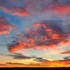 Vibrant sunset panorama with orange, red, and blue hues over silhouetted horizon