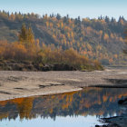 Tranquil river with autumn trees and sandy shore