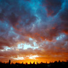 Vibrant sunset with fiery orange hues over forested horizon