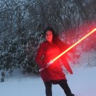 Red lightsaber-wielding character in snowy forest scene