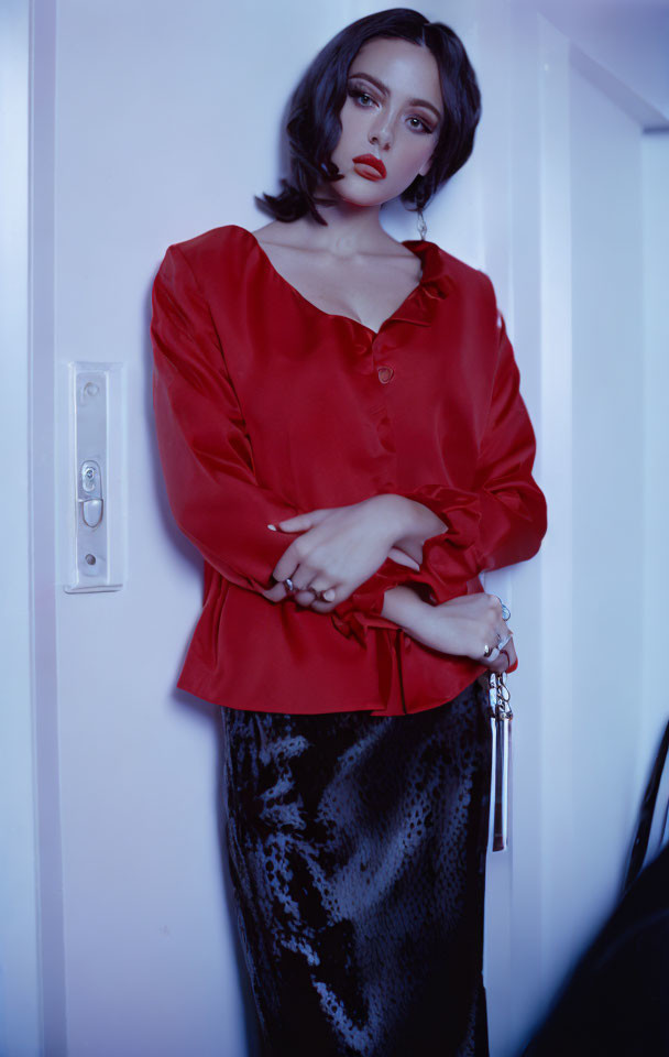 Woman in red blouse and sequined skirt holding keys in dimly lit room