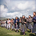 Group of people dancing outdoors in expressive poses on grassy field under cloudy sky