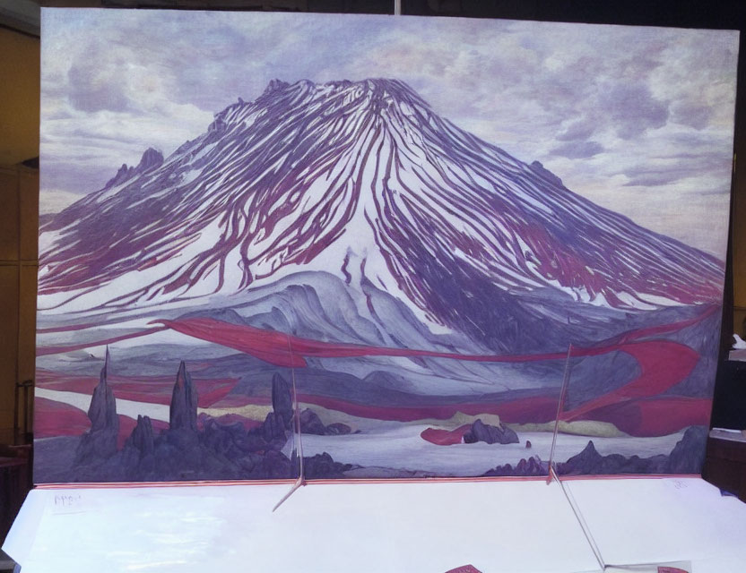 Snow-capped mountain with red streaks under cloudy sky and rocky terrain.