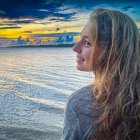 Digital artwork of woman with curly hair admiring seascape at sunset