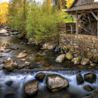 Tranquil stream with moss-covered rocks near rustic autumnal watermill