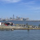 City skyline with skyscrapers under blue sky and birds, over water with boats