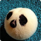 Round beige fluffy toy with dark center on blue textured surface