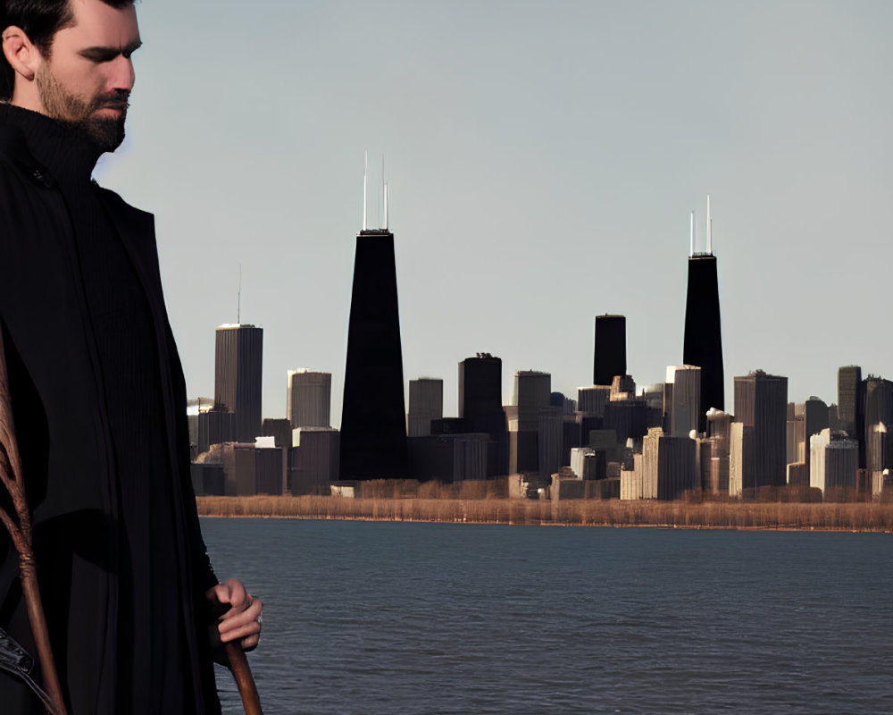 Man with staff by water and city skyline in clear sky