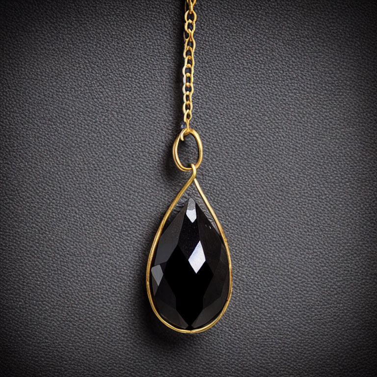 Black Gemstone Pendant with Gold Setting on Textured Background