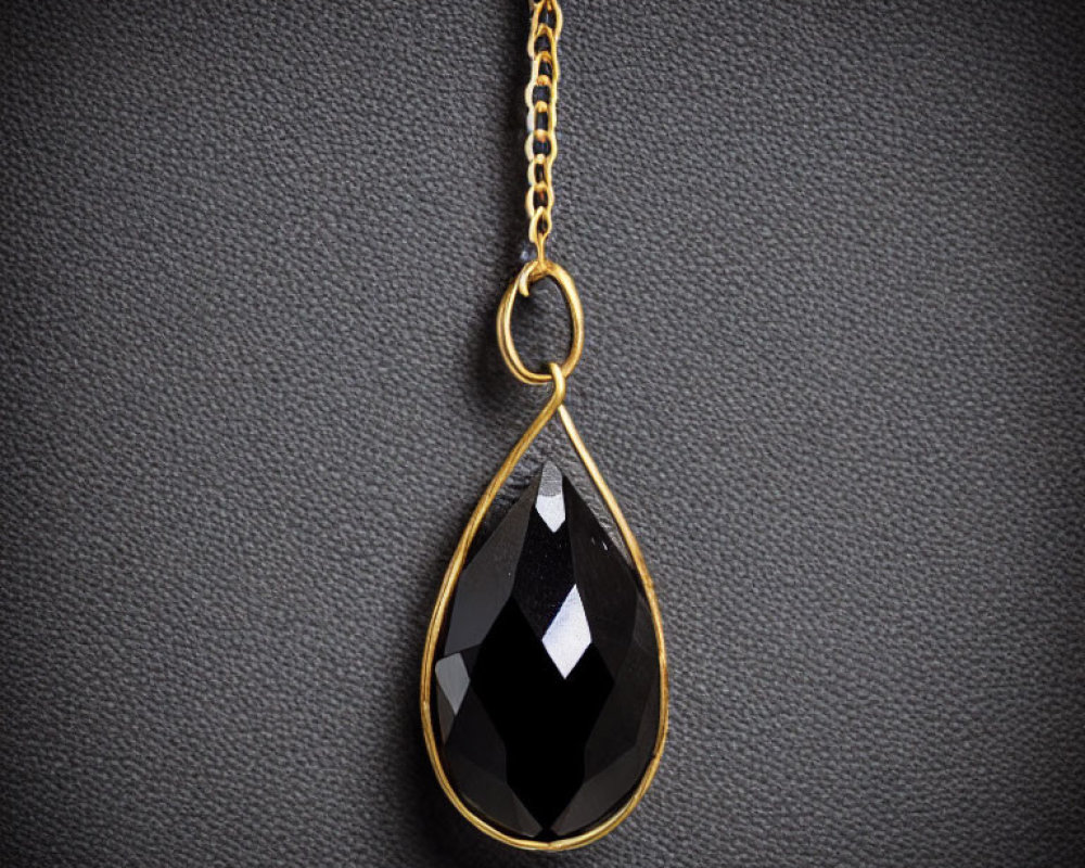 Black Gemstone Pendant with Gold Setting on Textured Background