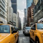 City street with yellow taxis, rainy day, tall buildings, vibrant lights