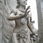 Regal woman in golden headpiece and drapery near ornamental pillars