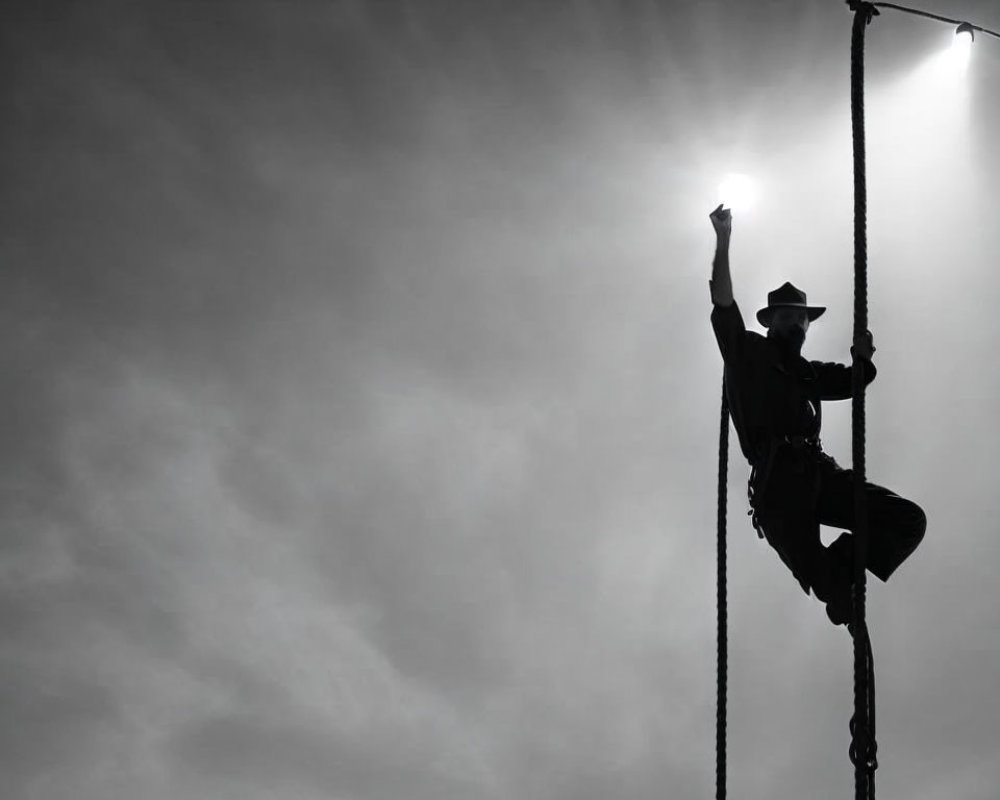 Silhouette of person climbing ladder under sun halo